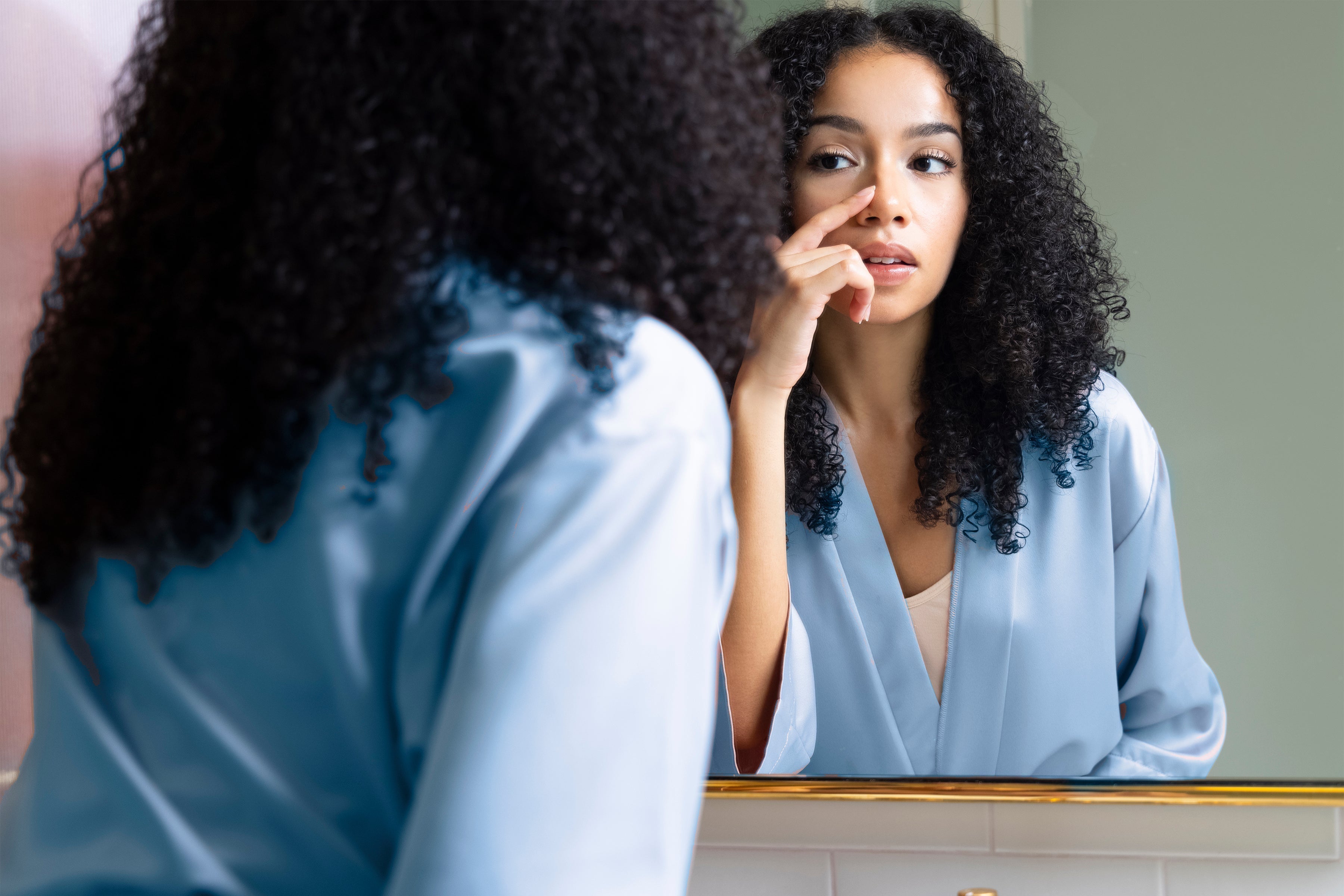 A woman looking at her pores in a mirror.