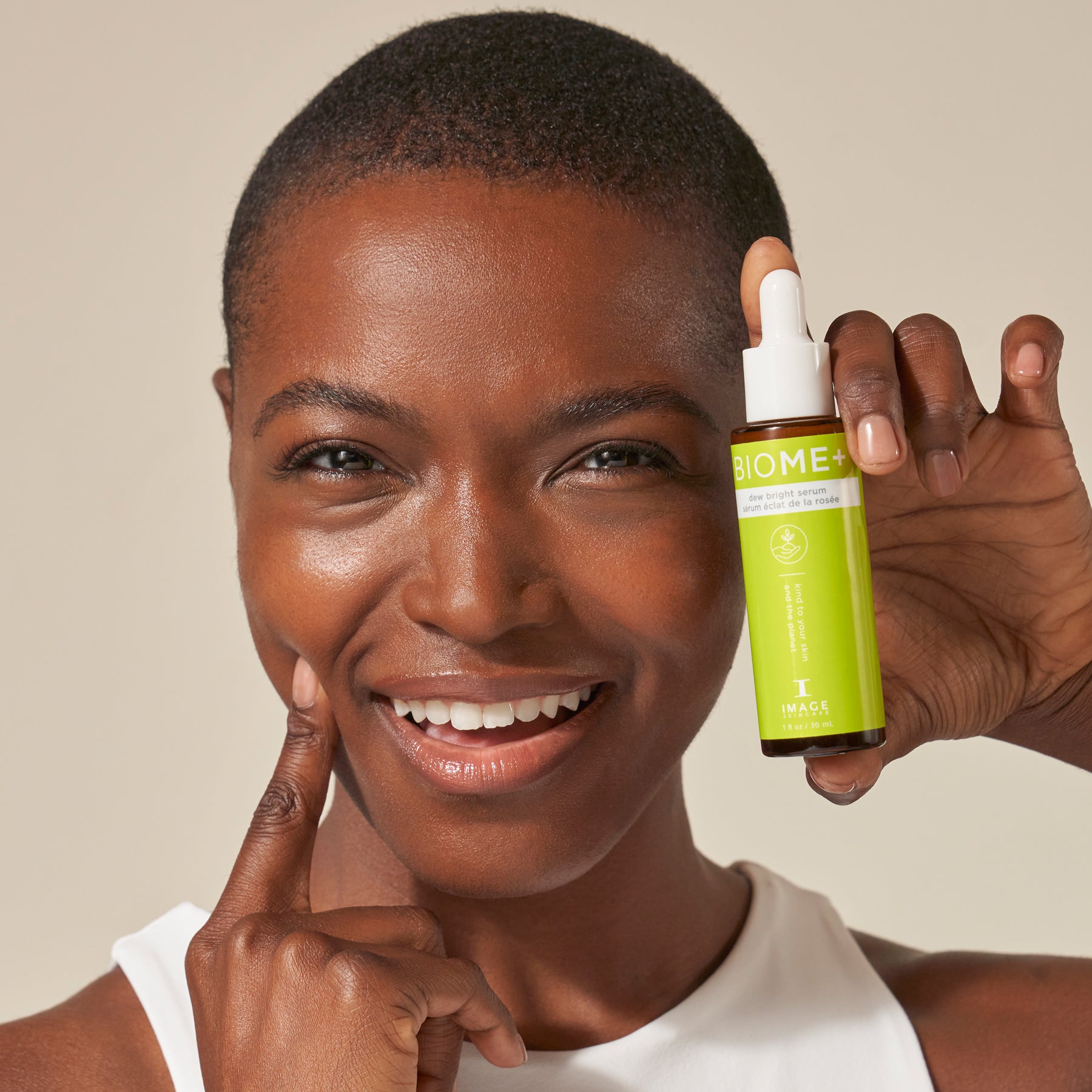 model holding biome+ dew bright serum bottle up to her face