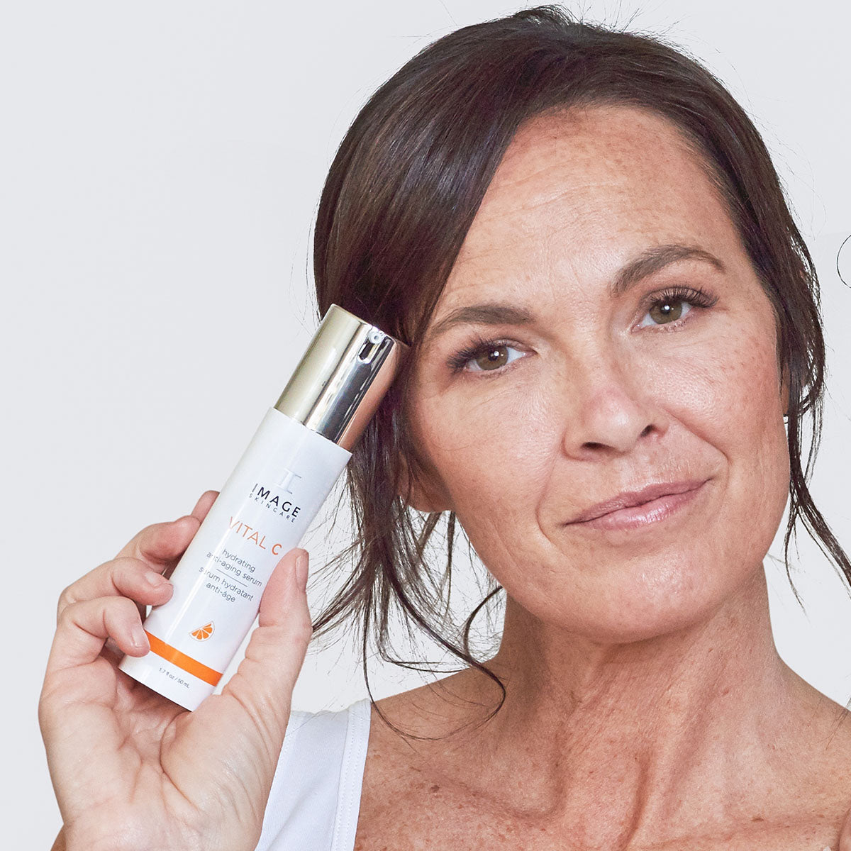 Woman holding a bottle of Image Skincare anti aging vitamin C serum VITAL C.