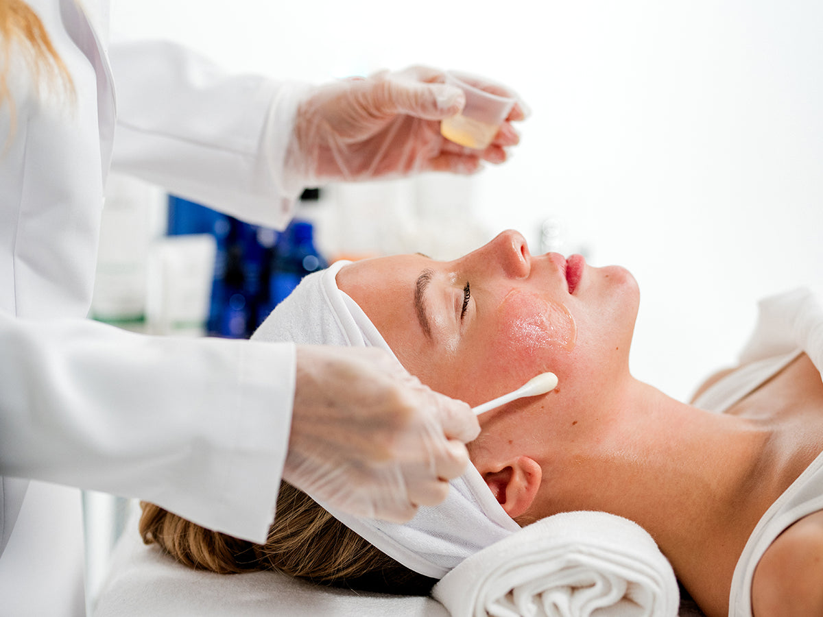 A woman is lying down receiving a chemical peel. 