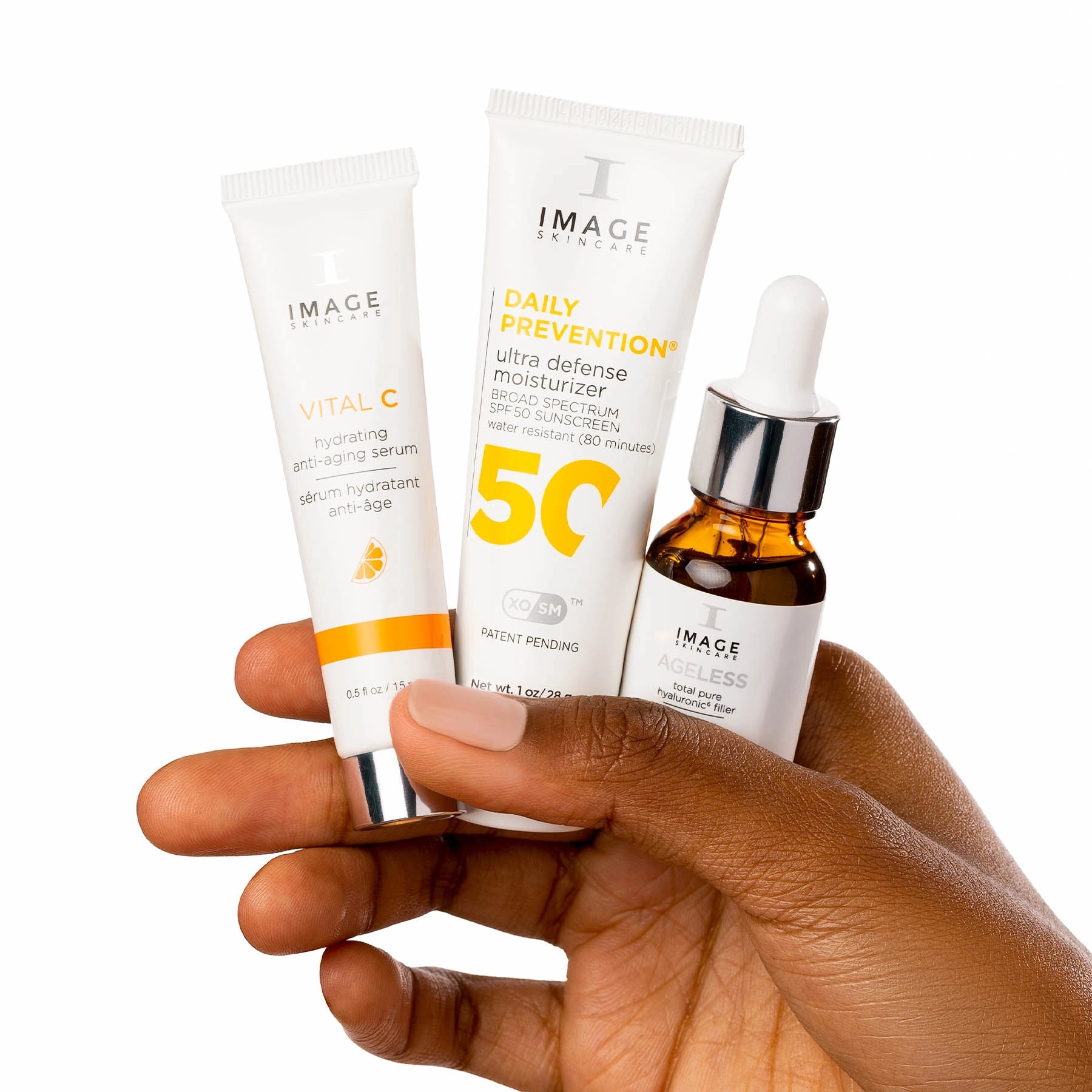 Hand holding skincare products including a tube, bottle, and dropper with 'IMAGE' branding on a white background.