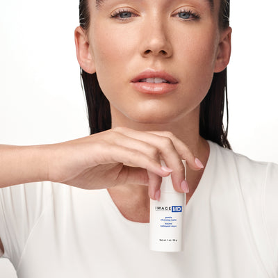 Woman holding a skincare product with 'IMAGE MD' branding against a white background