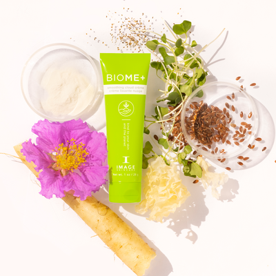 Biome+ smoothing cloud creme travel size tube laid in between petri dishes with ingredients and plant leaves
