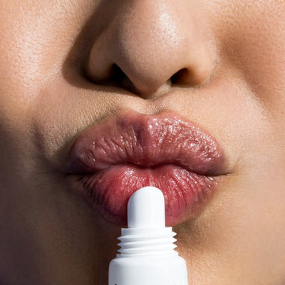 Close-up of a person applying lip balm to their lips.