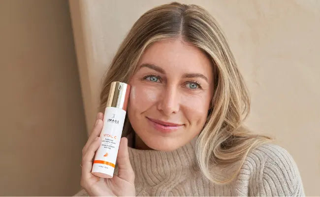 woman in Fall sweater holding skincare product