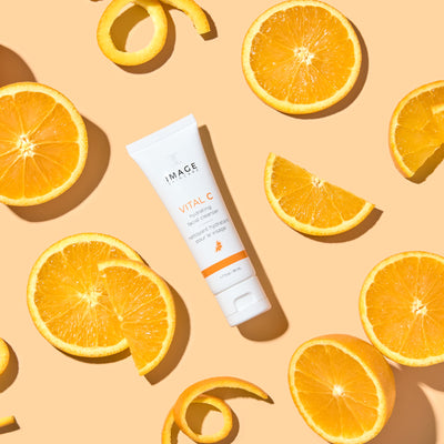 travel size cleanser on orange background with orange slices