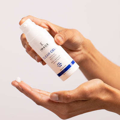 model hands holding bottle of acne lotion