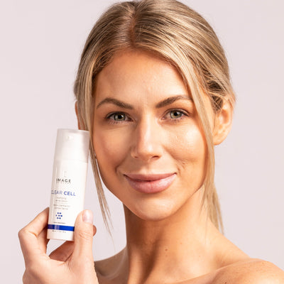 model holding acne lotion bottle up to face