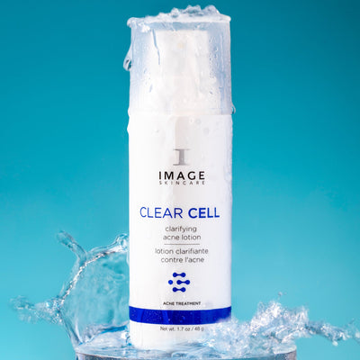 clear cell acne bottle lotion on blue background with water splashing on bottle