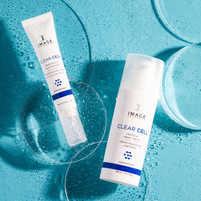 CLEAR CELL clarifying acne spot treatment and repair creme product bottles on blue background with bubbles
