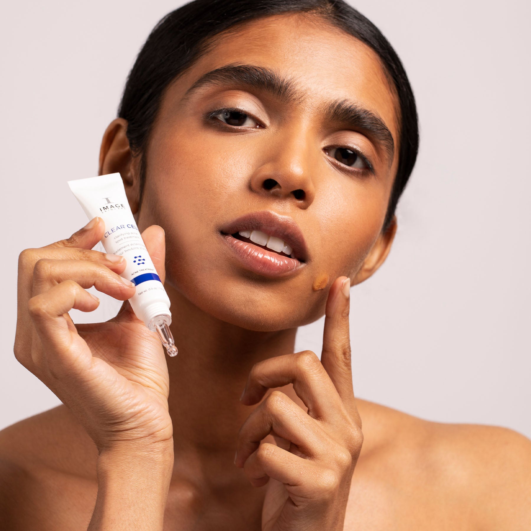 Woman holding clarifying acne spot treatment