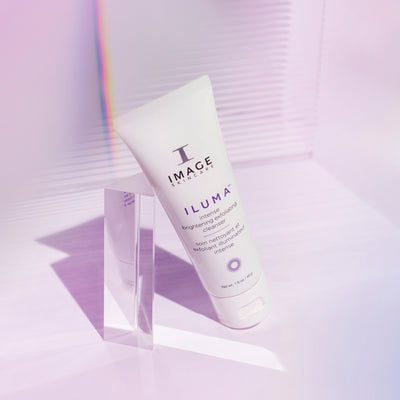 iluma cleanser travel size tube leaning against a prism on a light purple background