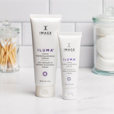 ILUMA exfoliating cleanser retail and travel size tube on a bathroom counter