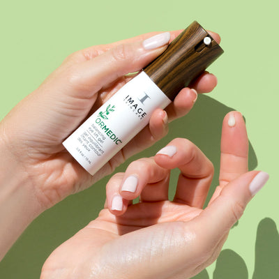 model hands holding product bottle dispensing product dot on finger