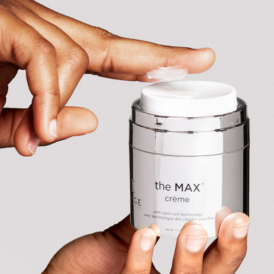 Max creme opened container with model hands applying product onto finger