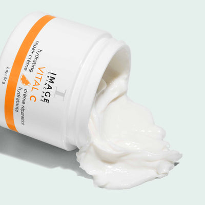 open bottle of repair creme spilling product on light background