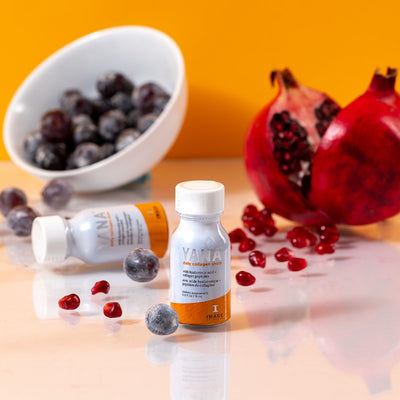 Yana bottle in front of sliced pomegranate and bowl of cherries